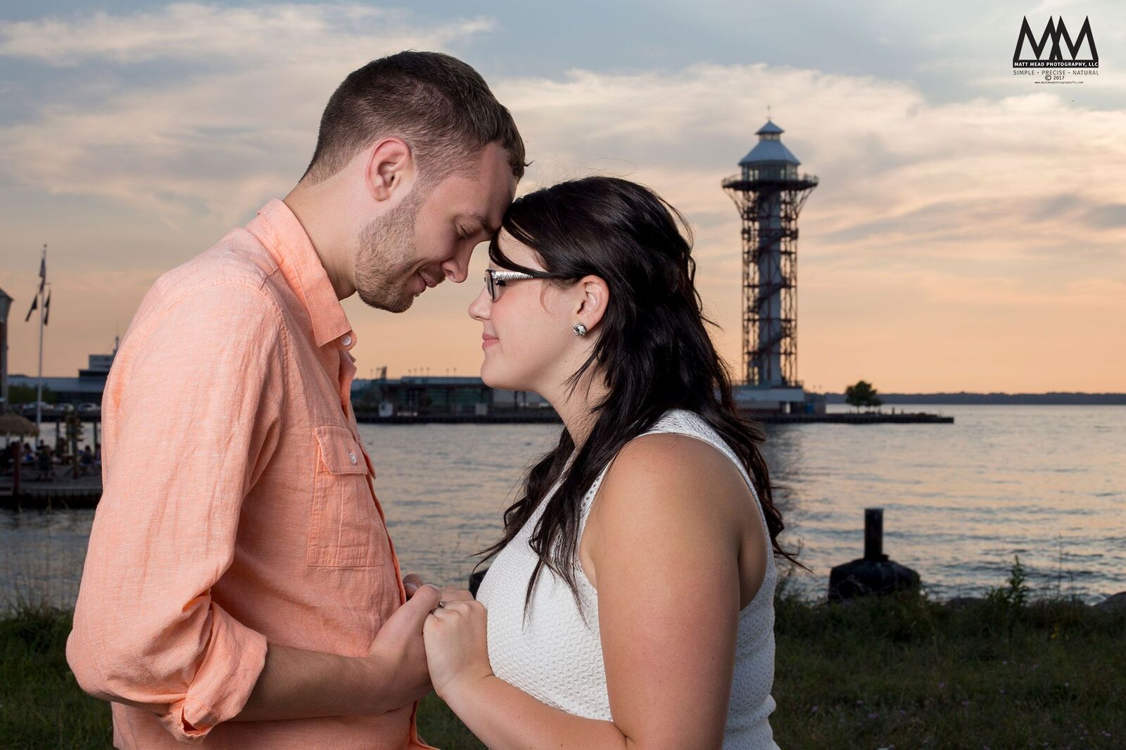 erie pa engagement photos holding hands in sunset in front of Bicentennial Tower on Dobbin's Landing