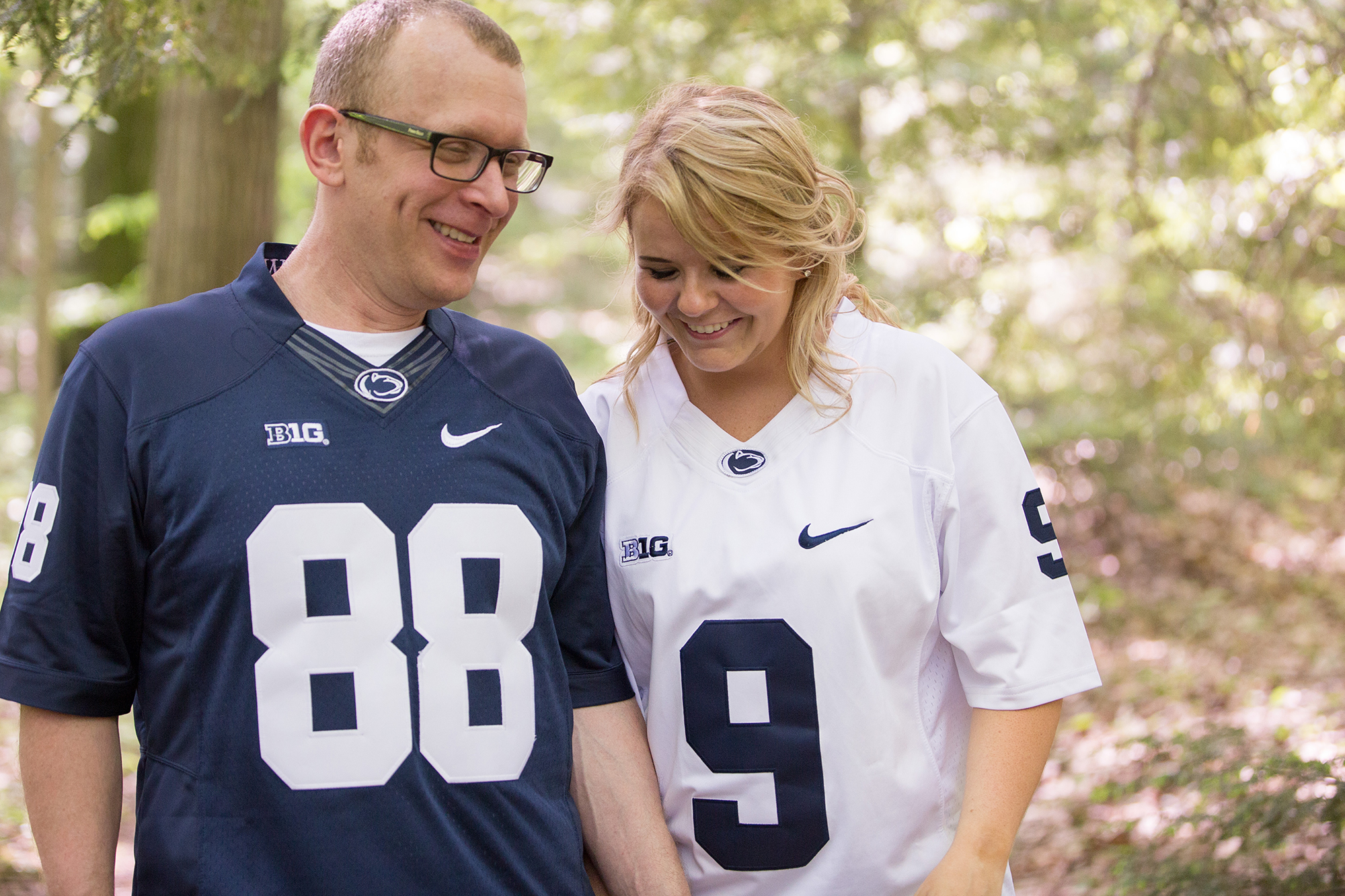 Couple wearing Penn State football jerseys walk through arboretum at Penn State Behrend in Erie, PA