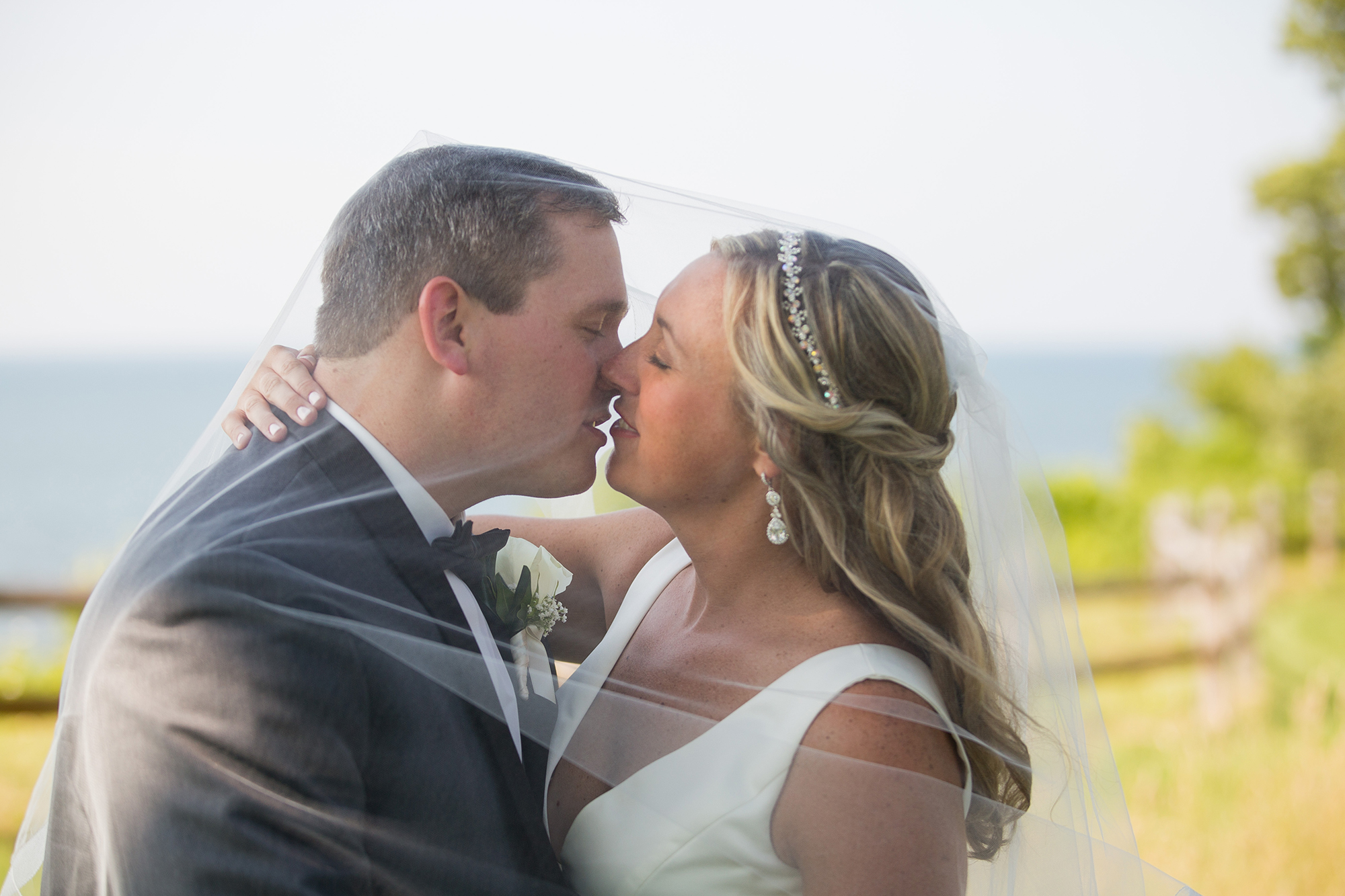 wedding couple shares a kiss under bride's veil during bridal portraits at Lawrence Park Golf Club