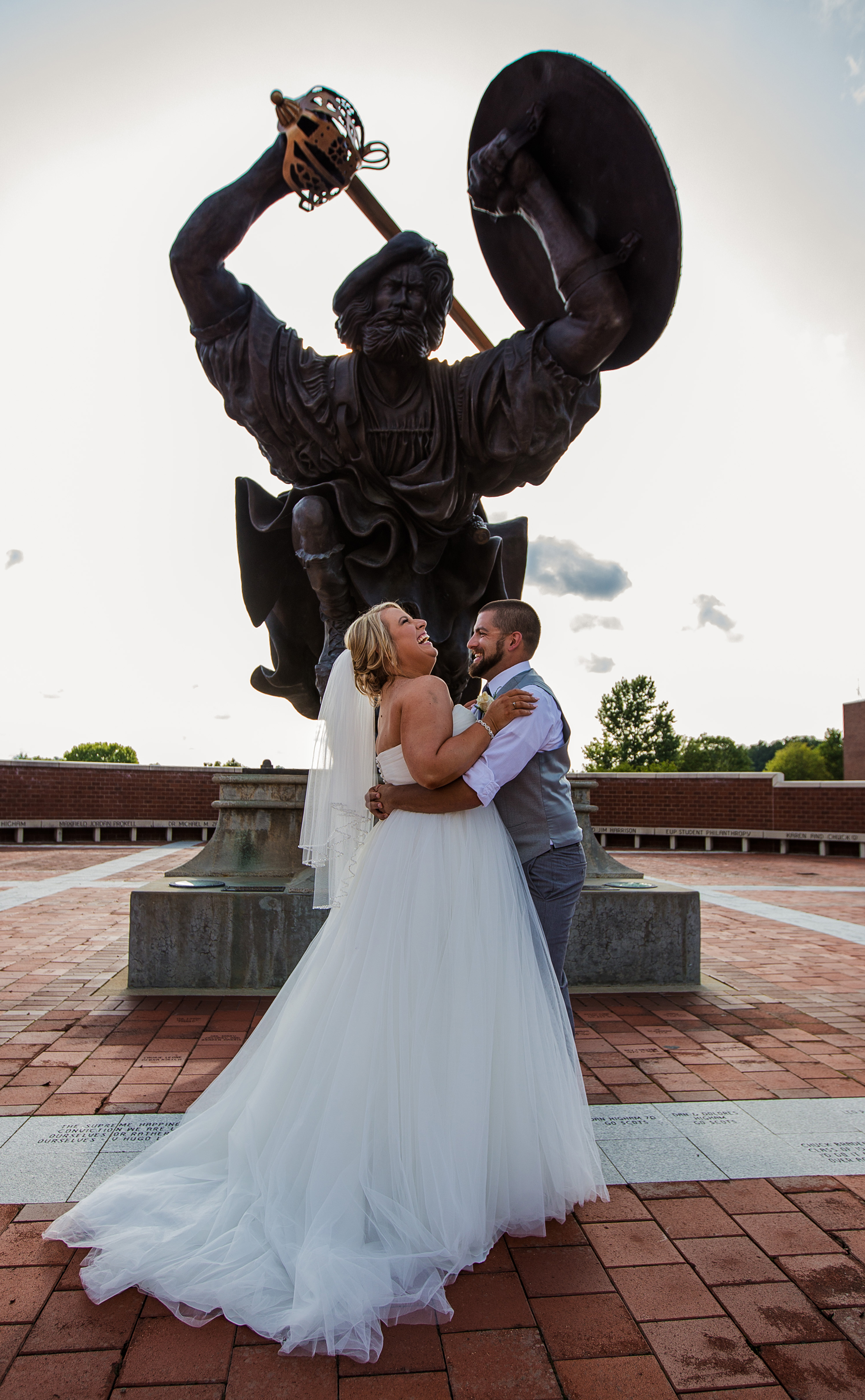 bride and groom laugh tigether while standing in front of Angus statue at Edinboro University wedding