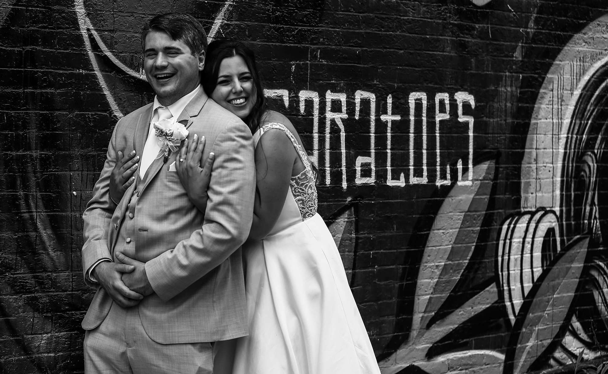 Bride and groom pose together in front of graffiti filled wall in Pittsburgh, PA