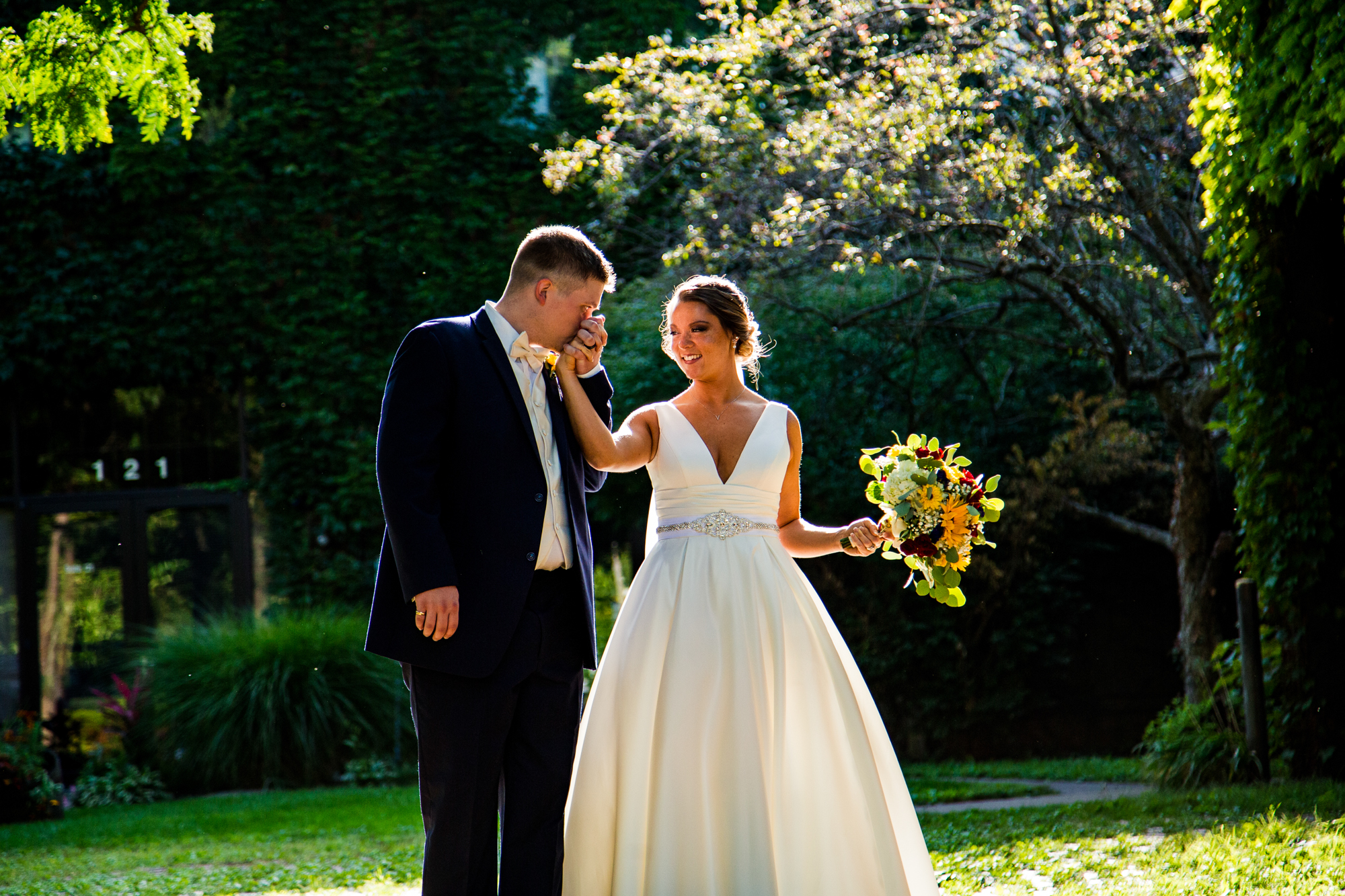 Groom kisses bride's hand during wedding day portraits at Modern Tool Square