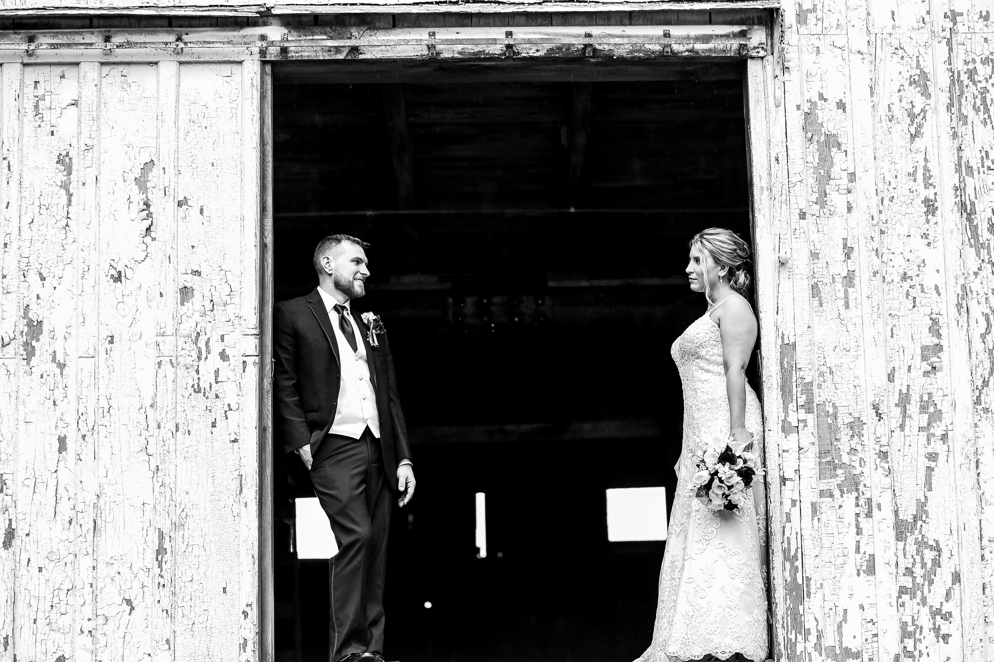 Groom smiles at bride on the second floor of the barn at Barn at Conneaut Creek wedding