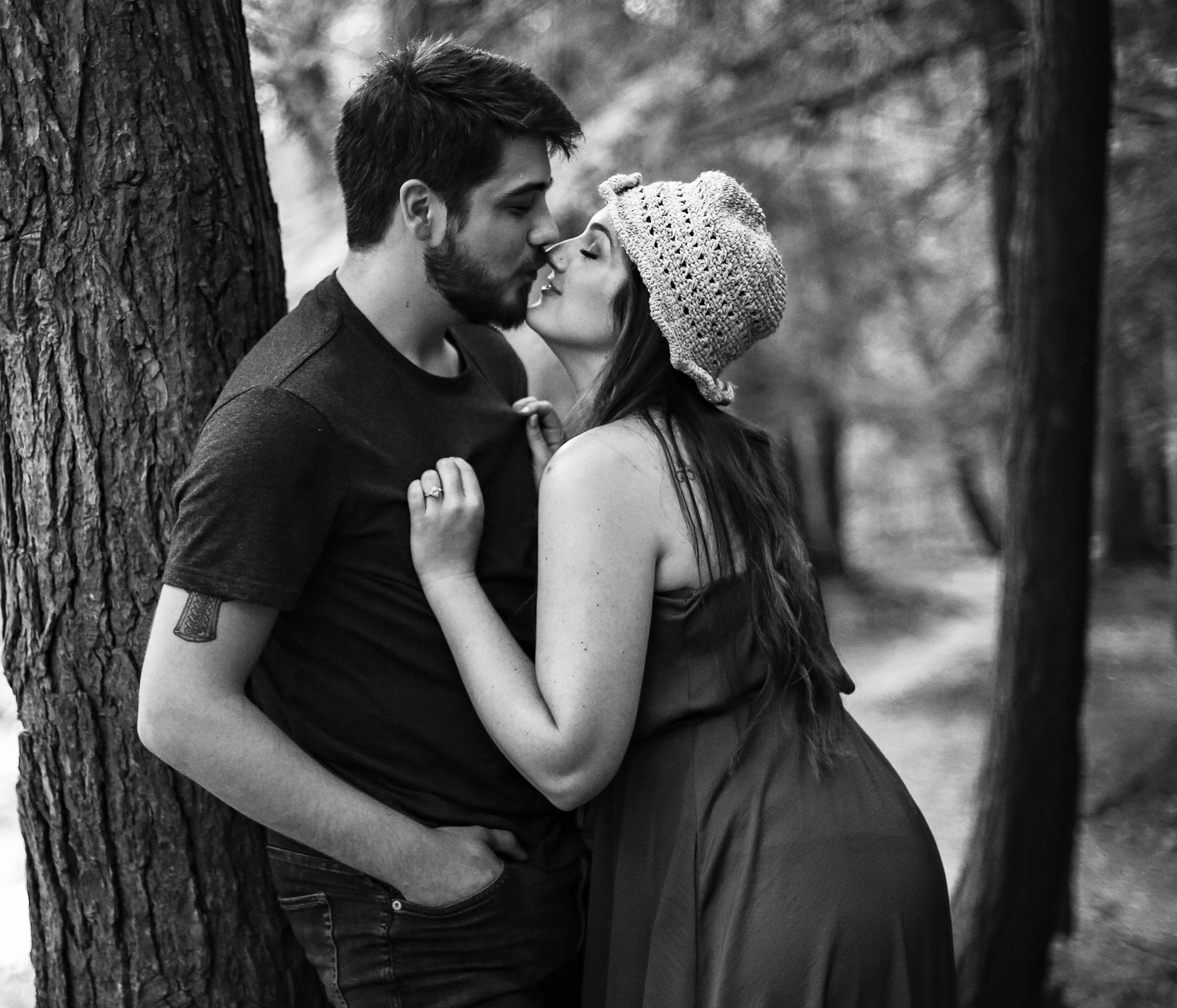 During engagement photos at Wintergreen Gorge woman leans in to kiss man leaning against a tree