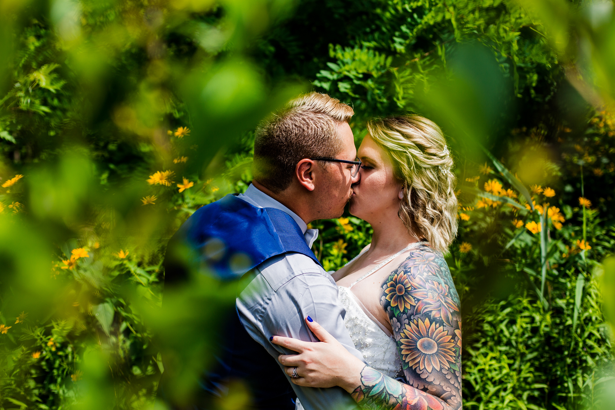 Portrait of couple kissing taken through leaves and trees