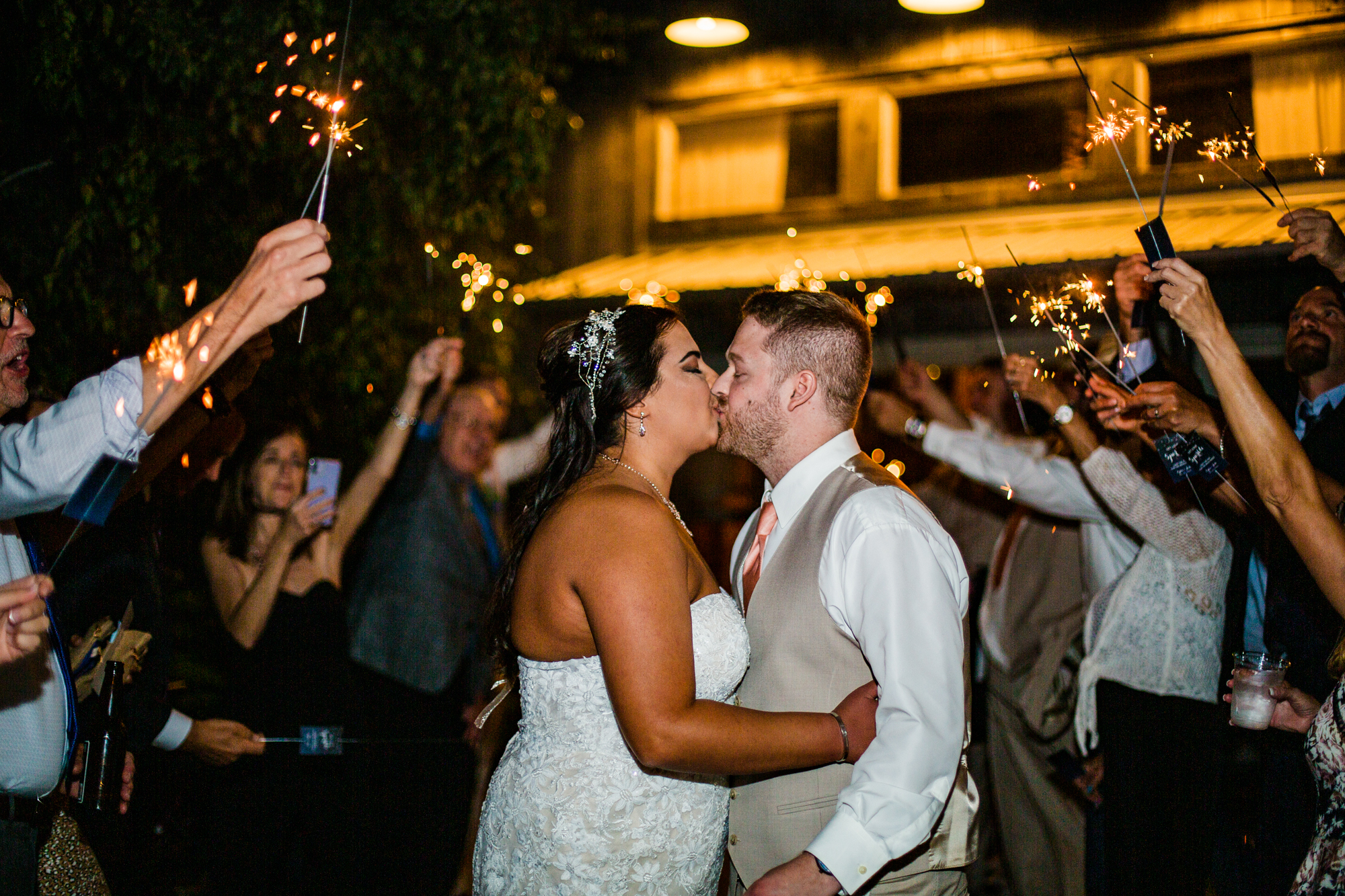 Bride and groom kissing during sparkler exit at the end of their Port Farms wedding