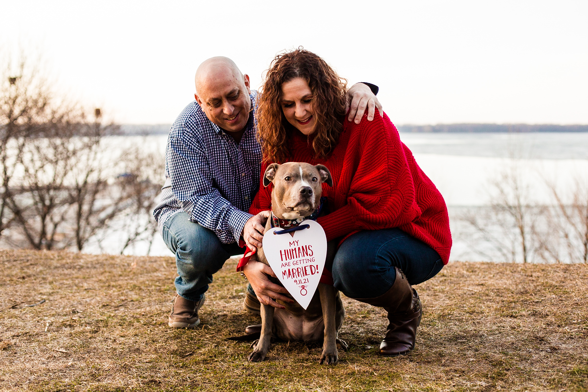 Couple poses with their dog wearing a save the date sign