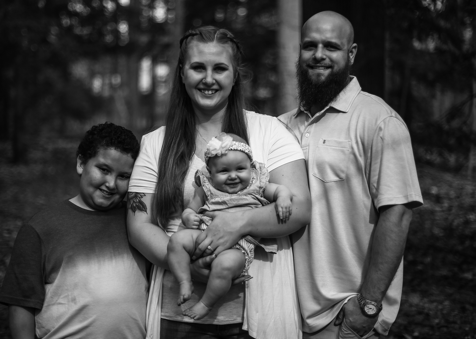 Man, woman, boy and baby smile at th camera for family photos at Asbury Woods