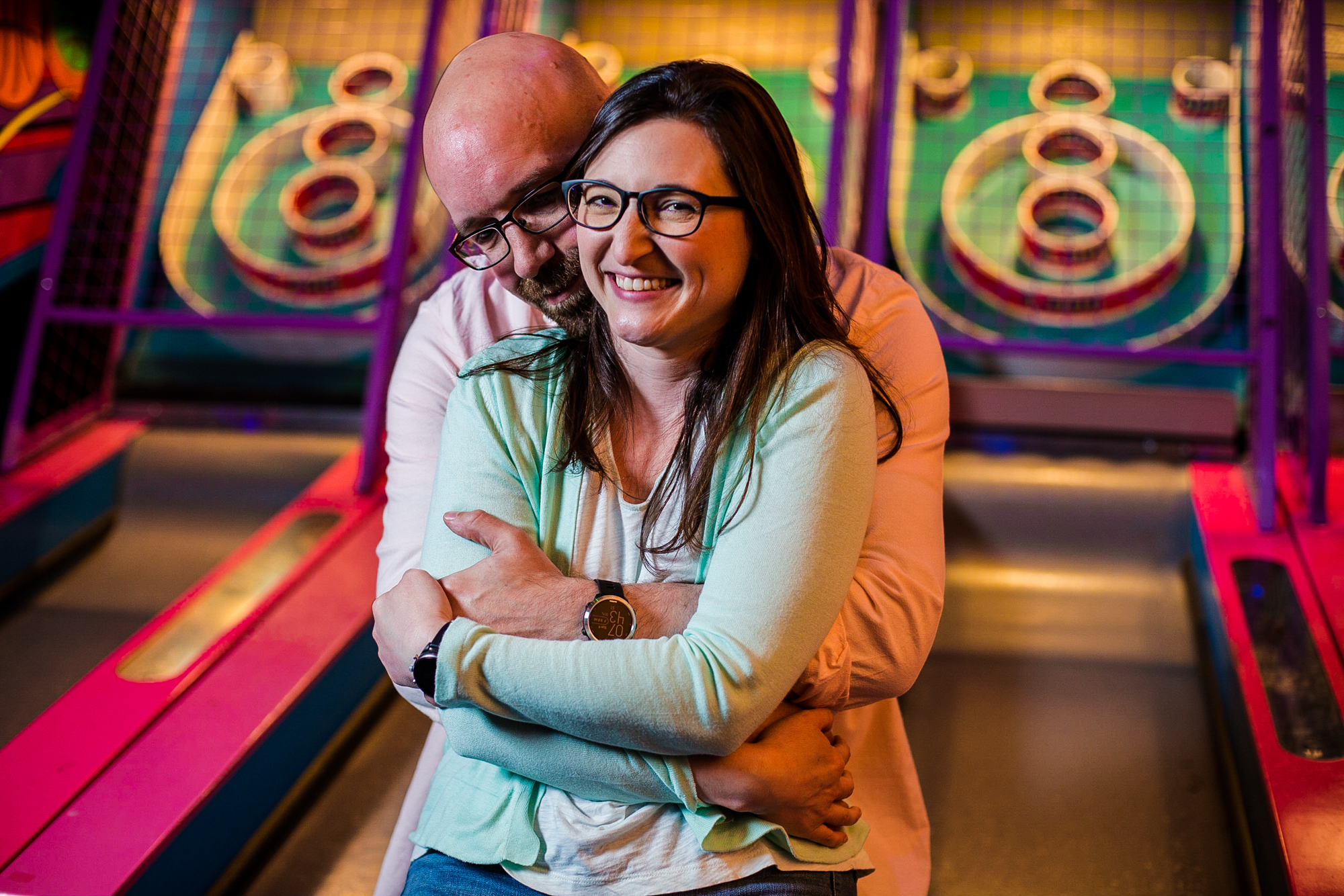Couple hugs at the skee ball lanes at Play Port Erie for arcade themed engagement photos