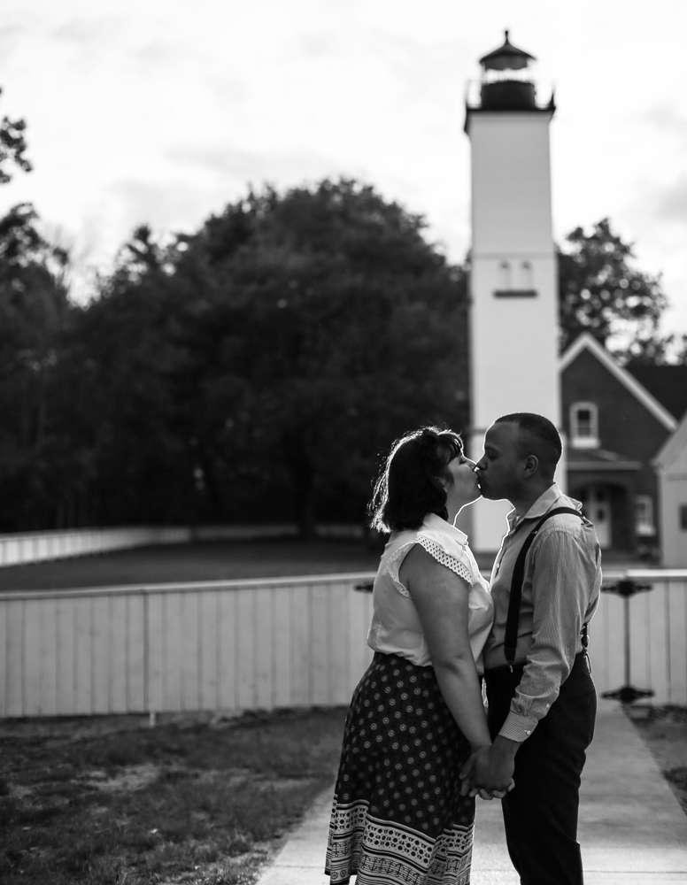 Couple kissing in front of lighthouse for Presque Isle Lighthouse engagement photos