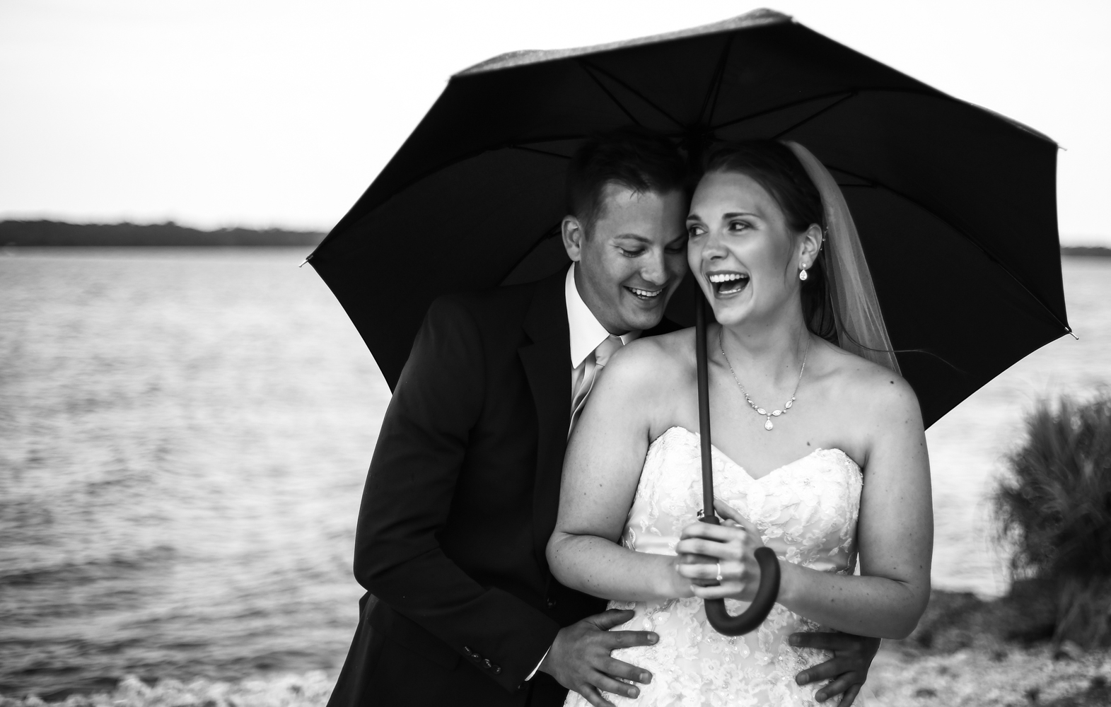 Laughiing couple standing under umbrella at Erie Yacht Club wedding