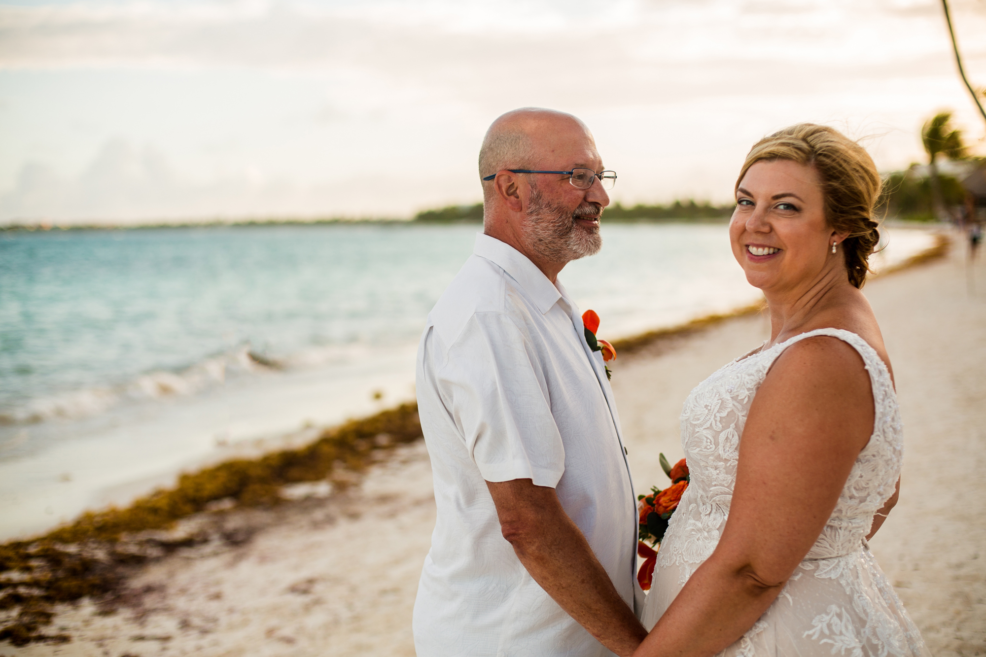 Groom looking at bride while she looks at camera on a beach at Secrets Akumal Riviera Maya