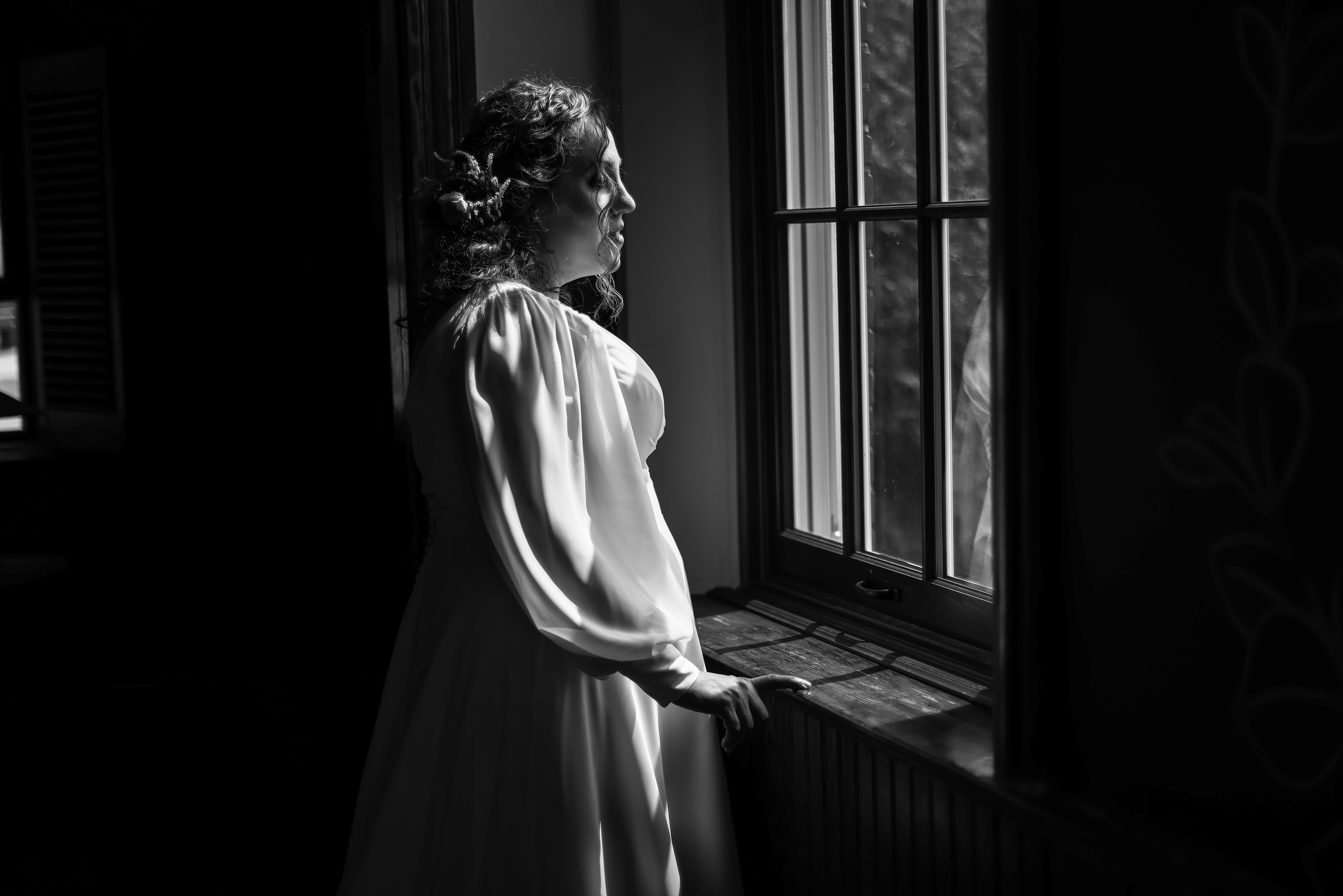 A bride ready and waiting in front of sunlit window.