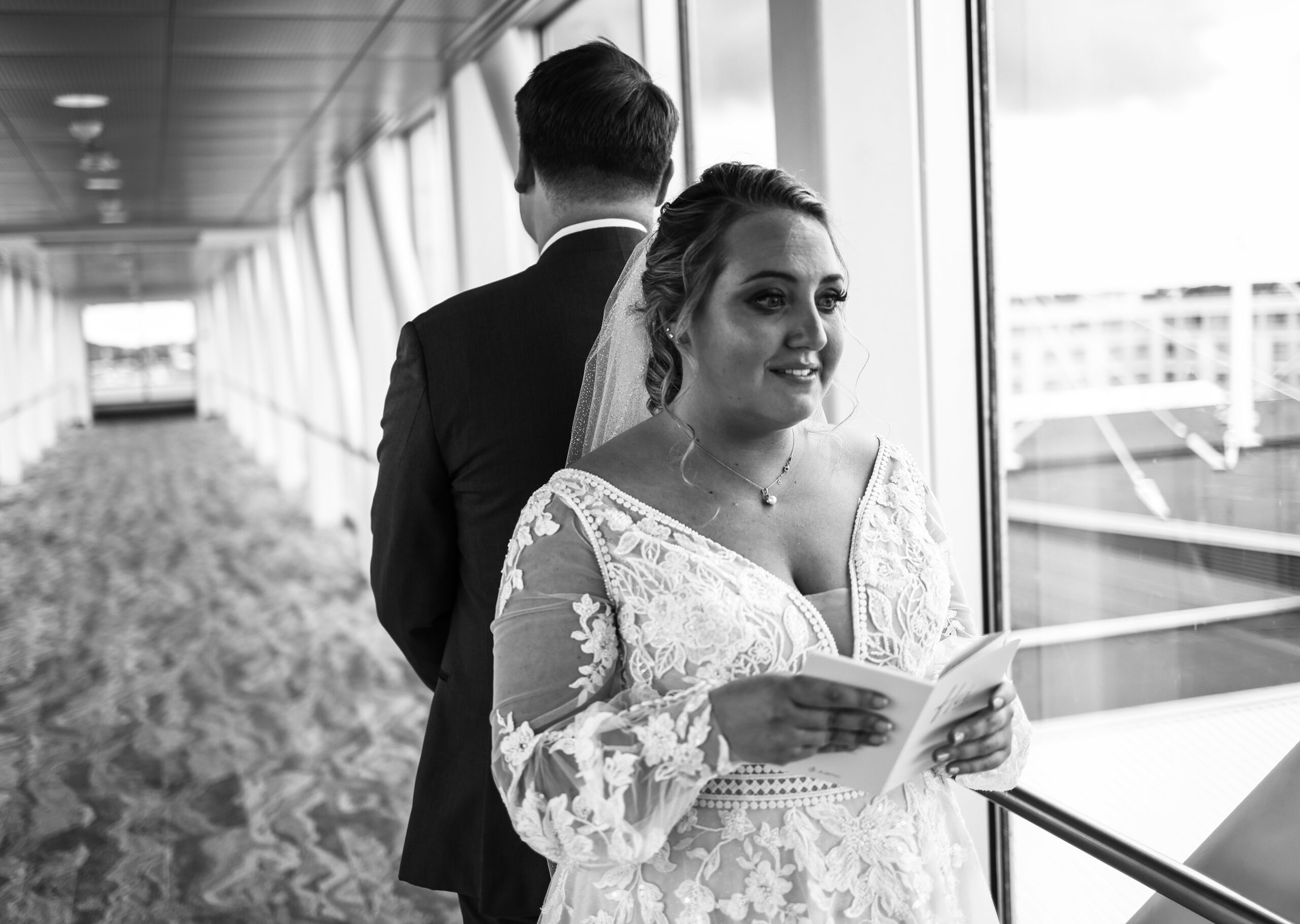 Bride and groom stand back to back waiting to do private vows and first look on the skybridge at the Bayfront Convention Center